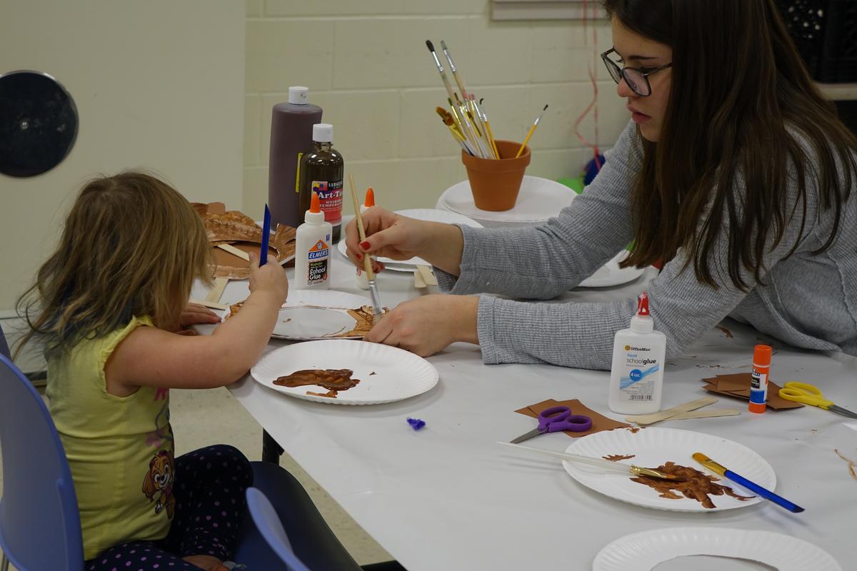 A student and child working on a craft